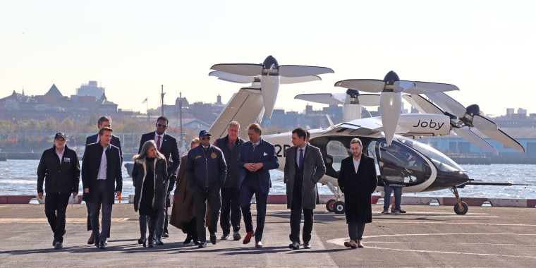 NYC Mayor Adams and leaders walking in front of an electric vertical take-off and landing (eVTOL) aircraft.