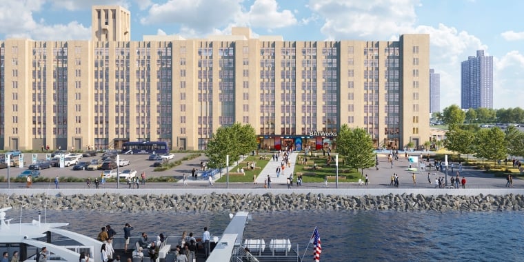 Exterior rendering of BATWorks shows a white NYC Ferry with passengers sailing along the waterfront. Behind it, a large tan building labeled BATWorks stands, with a green lawn, people walking, and trees in front. The sky is partly cloudy.